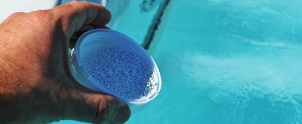person pouring bromine powder into a spa pool